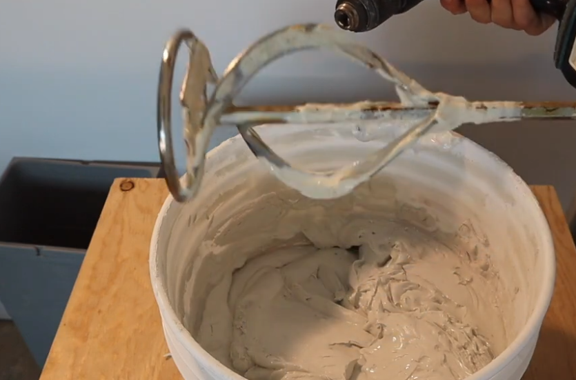 A person is mixing a mixture in a bowl with a mixer.