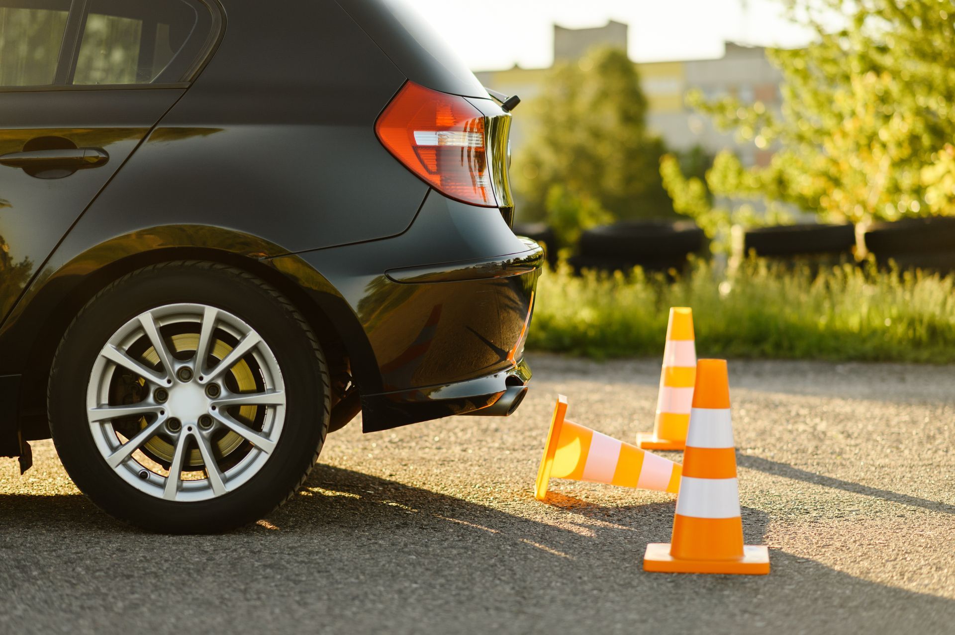 Black car next to orange and white traffic cones on asphalt. Black car next to orange and white traffic cones on asphalt.