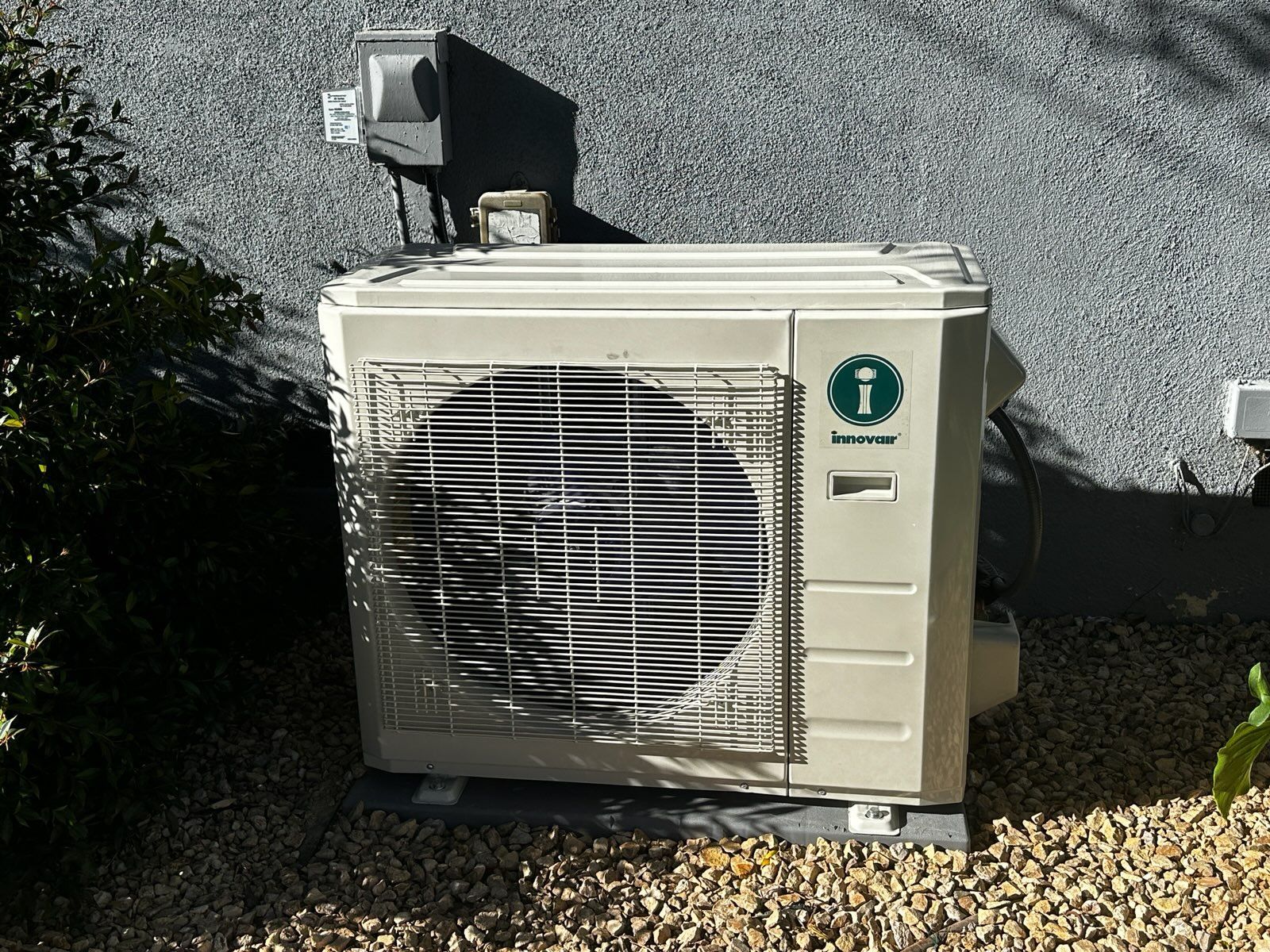 Air conditioning unit outside a building on gravel.