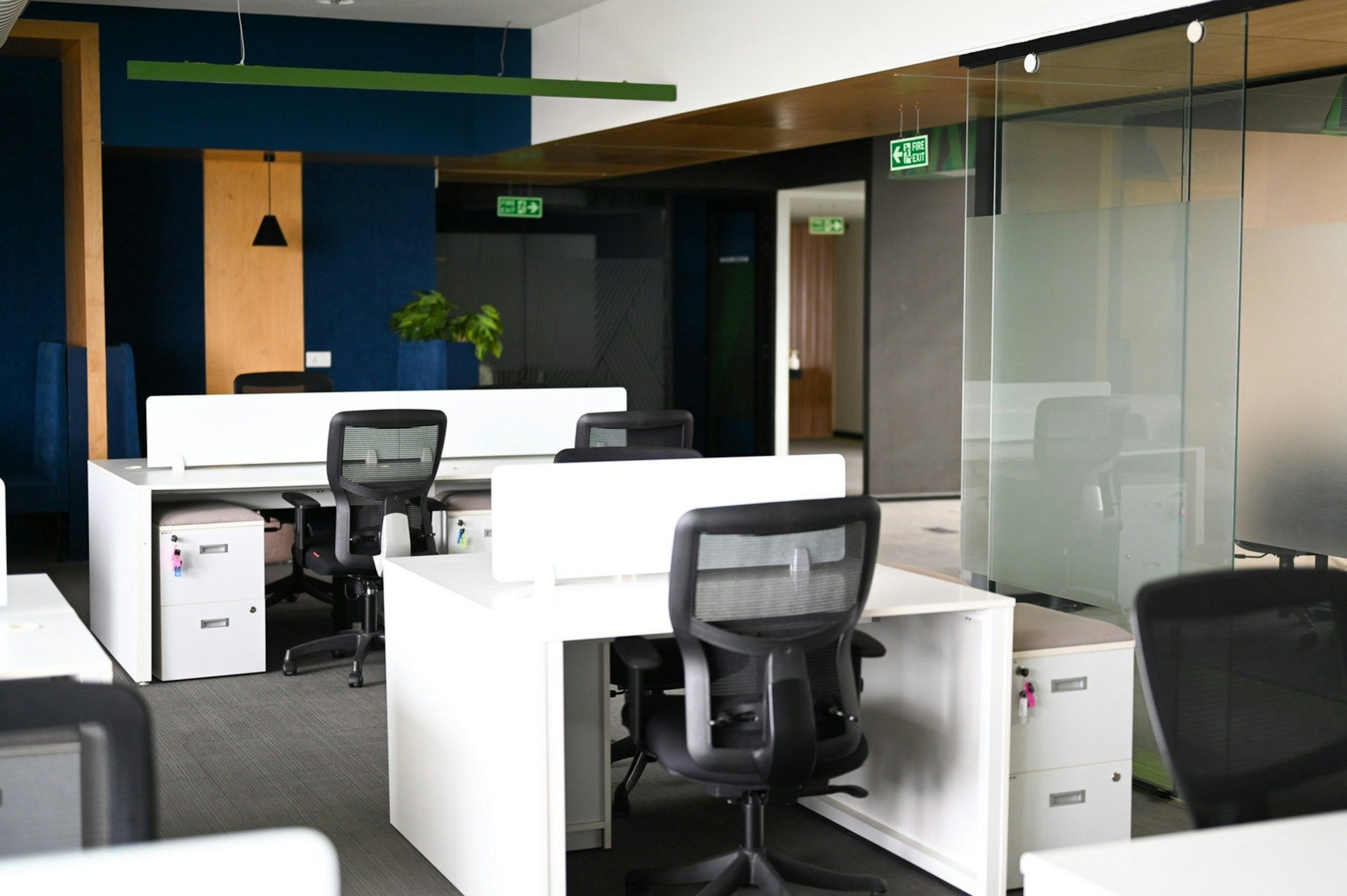 Modern office with white desks, black chairs, and glass partitions in an empty workspace
