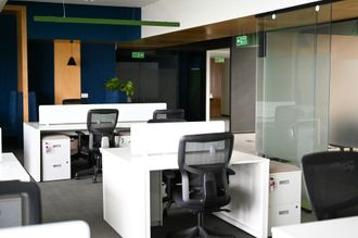 Modern office with white desks, black chairs, and glass partitions in an empty workspace