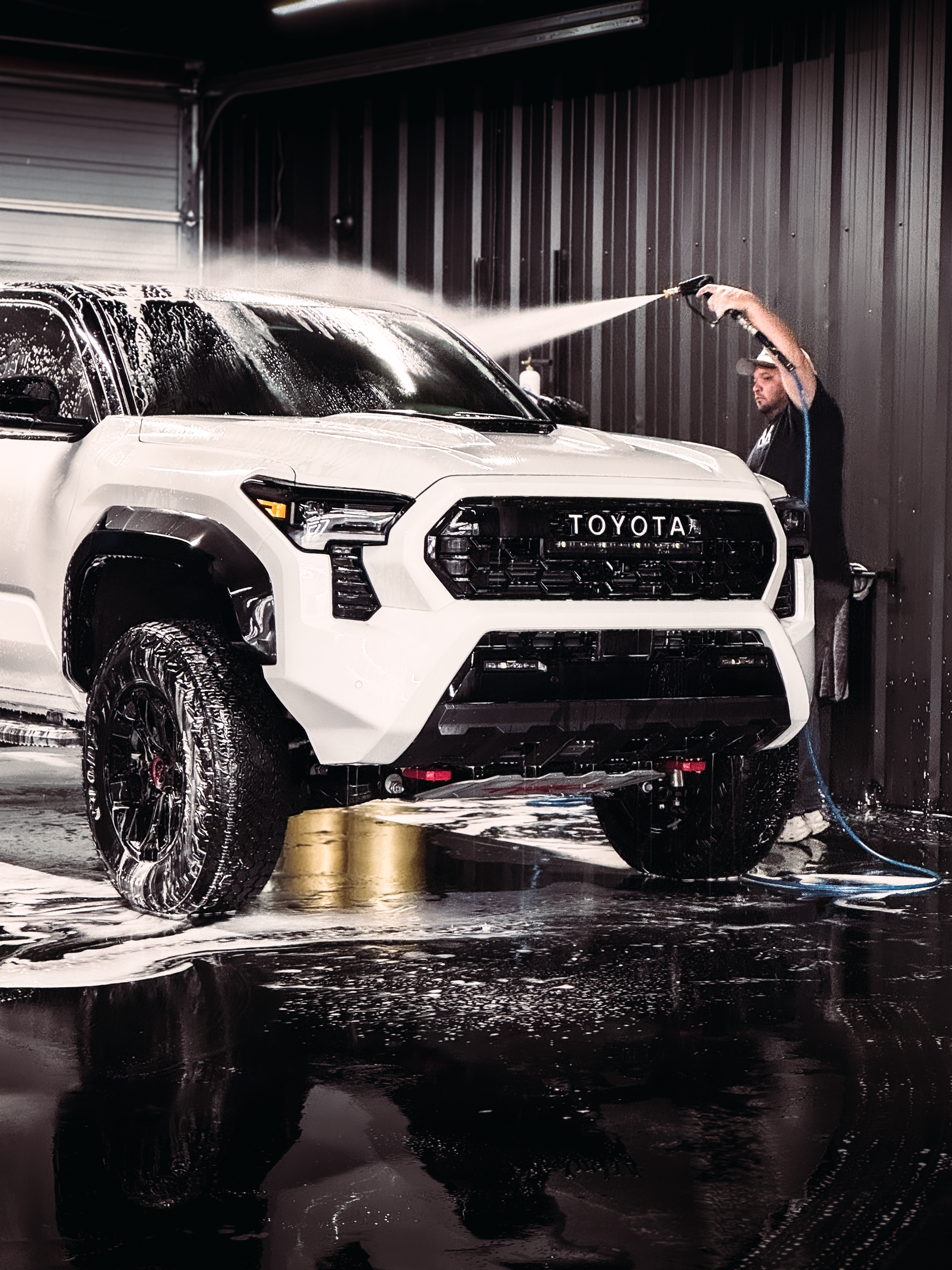 A car is being washed in a garage with its doors open.