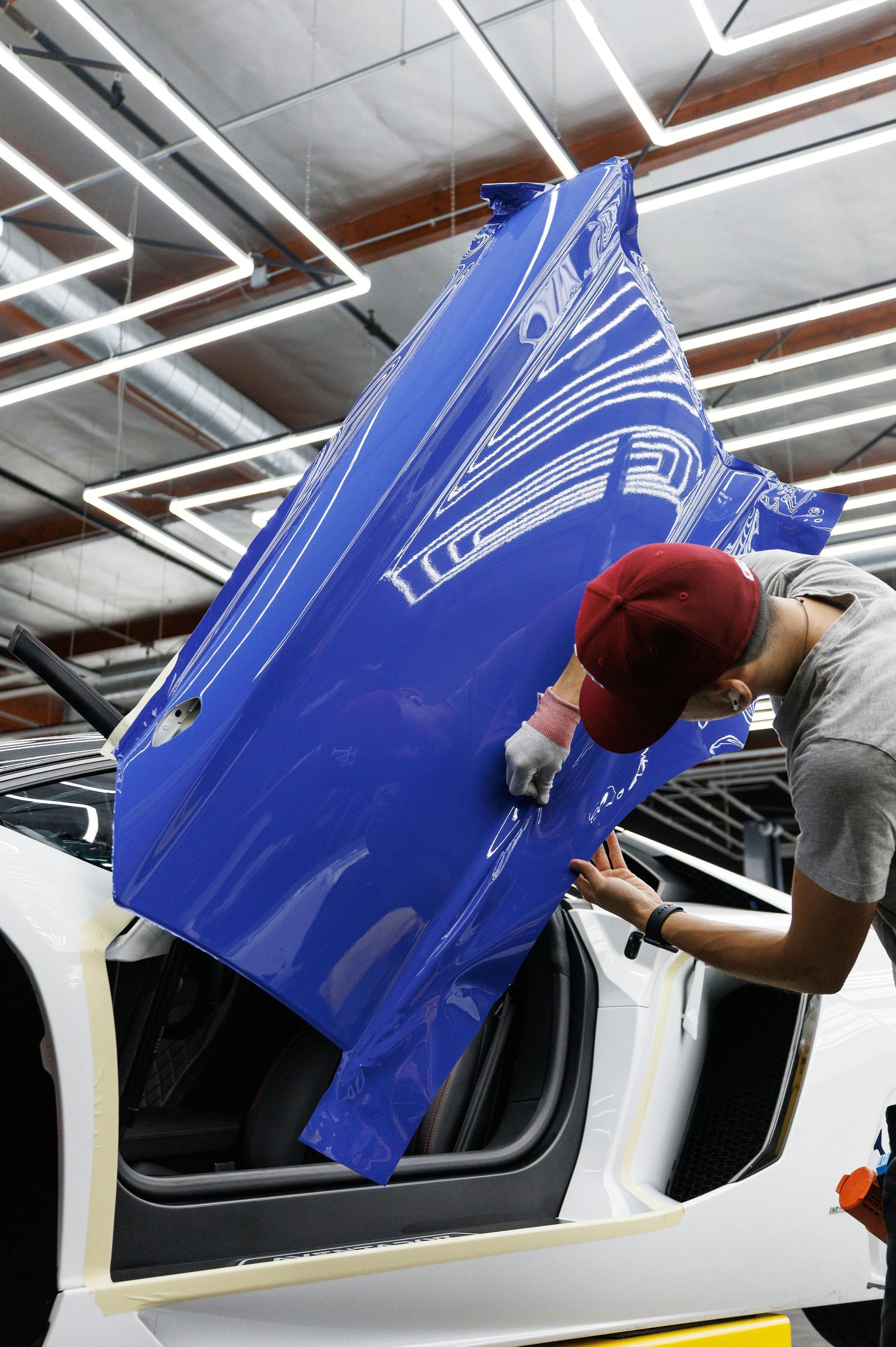 A man is working on a blue car in a garage.