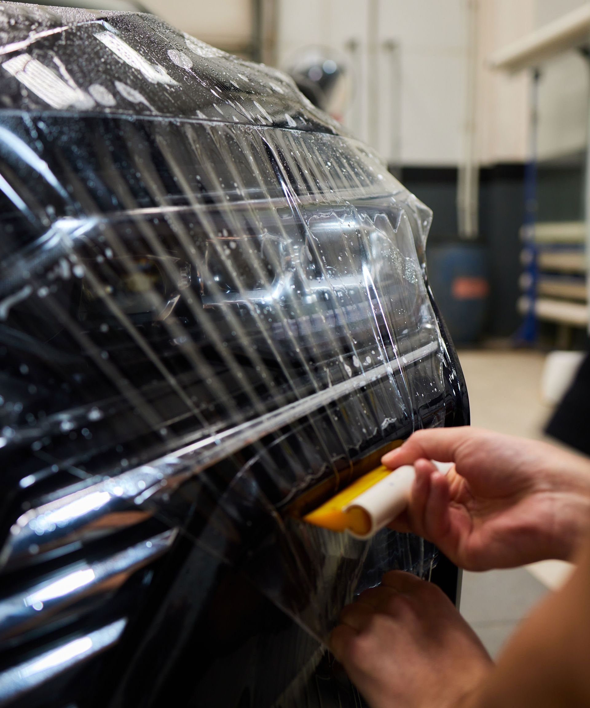 A person is wrapping a car with plastic wrap.