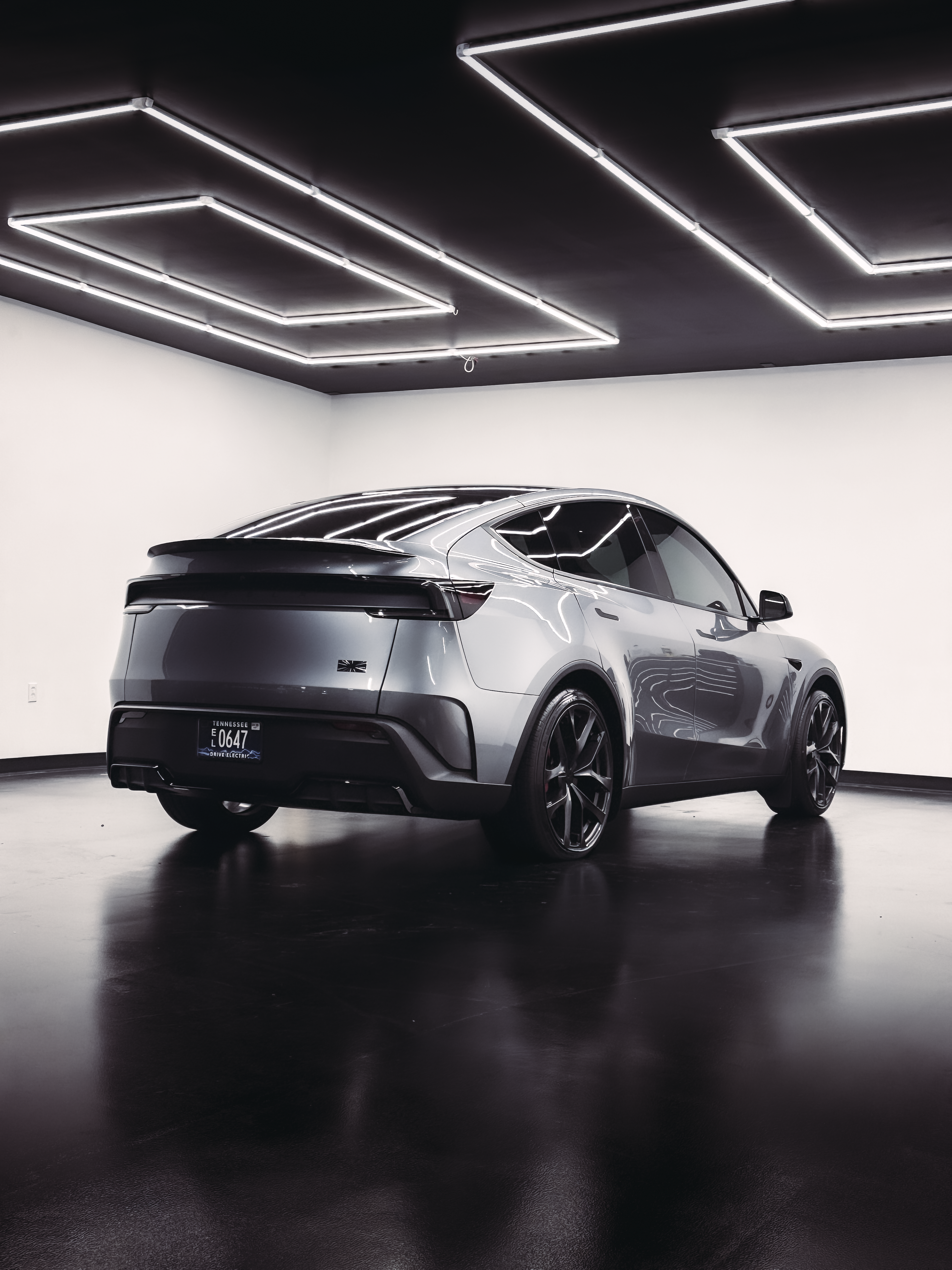 Gray electric car parked in a showroom with black and white lighting.