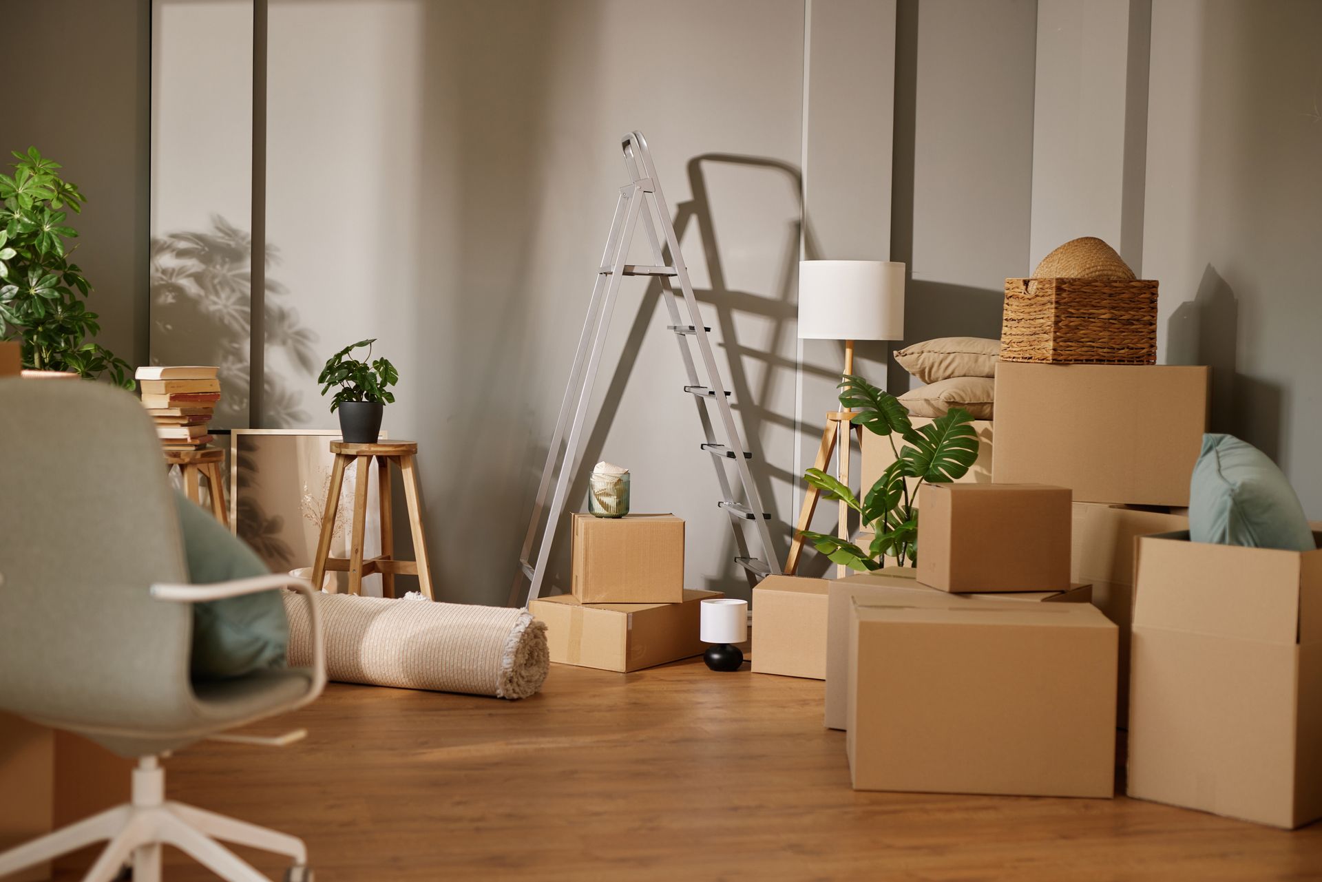 Moving boxes and a ladder in a bright room, suggesting a home move or renovation