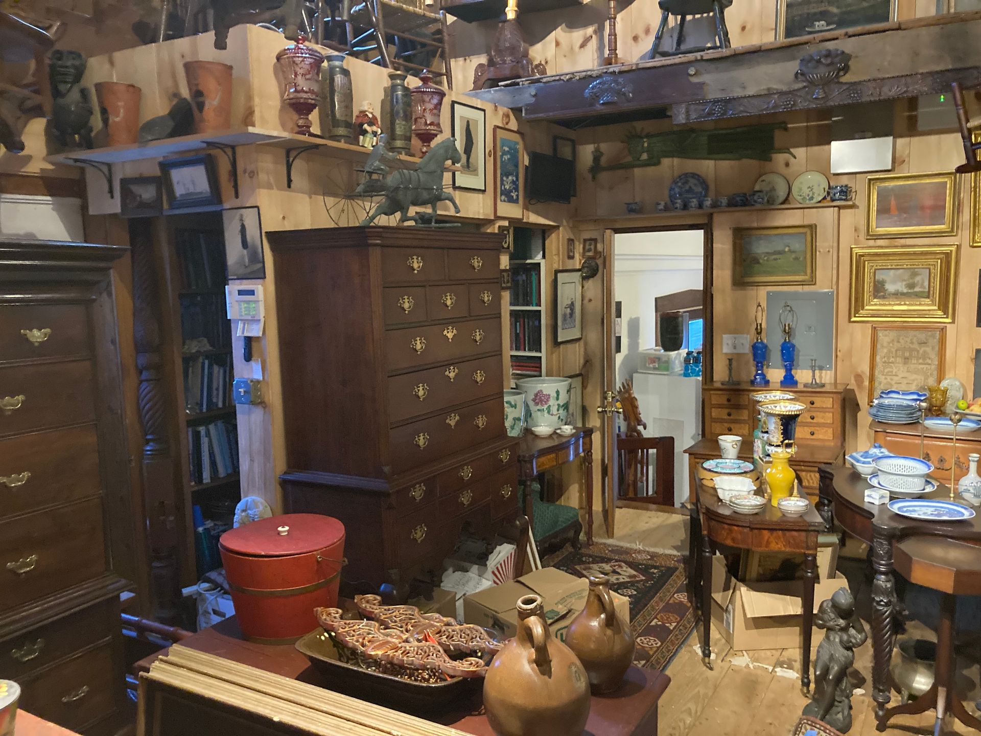 An antique-style wooden armoire with two upper doors featuring carved details and two lower drawers, in a furnished room.
