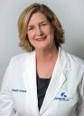 A woman in a white lab coat is smiling for the camera.