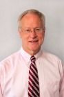 A man in a pink shirt and tie is smiling for the camera.