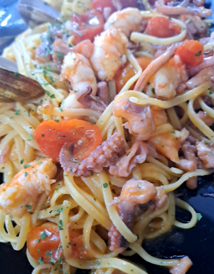 Spaghetti con pomodorini, funghi ed erbe aromatiche in una ciotola bianca