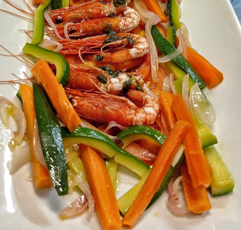 Saltato in padella con gamberi e verdure colorate su un piatto bianco.