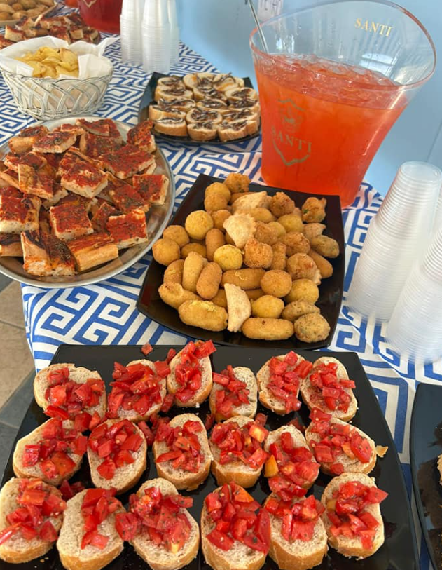 Antipasti assortiti e punch rosso su una tovaglia decorata a un tavolo da festa.