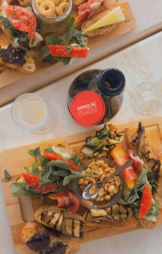 Due taglieri di legno con un assortimento di antipasti e bevande su un tavolo.