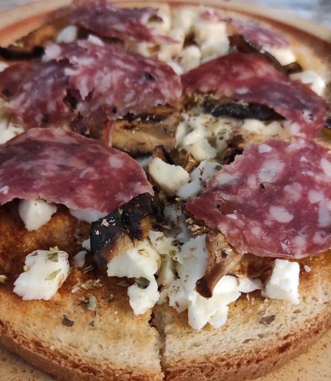 Tramezzino aperto con salame, formaggio sbriciolato e pane tostato su un piatto