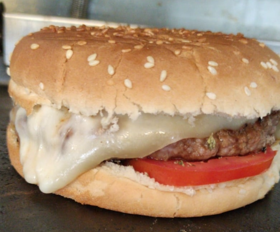 Cheeseburger in un panino al sesamo con formaggio fuso e una fetta di pomodoro