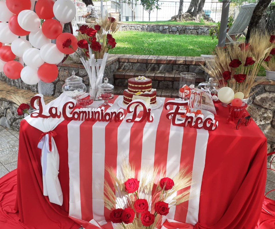 Tavolo dei dolci per la Prima Comunione in rosso e bianco con palloncini, rose e insegna