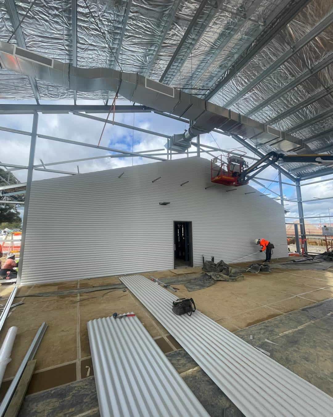 A Large Building Is Being Built With A Lot Of Metal Roofing — Kimick Roofing Solutions In Blacktown, NSW