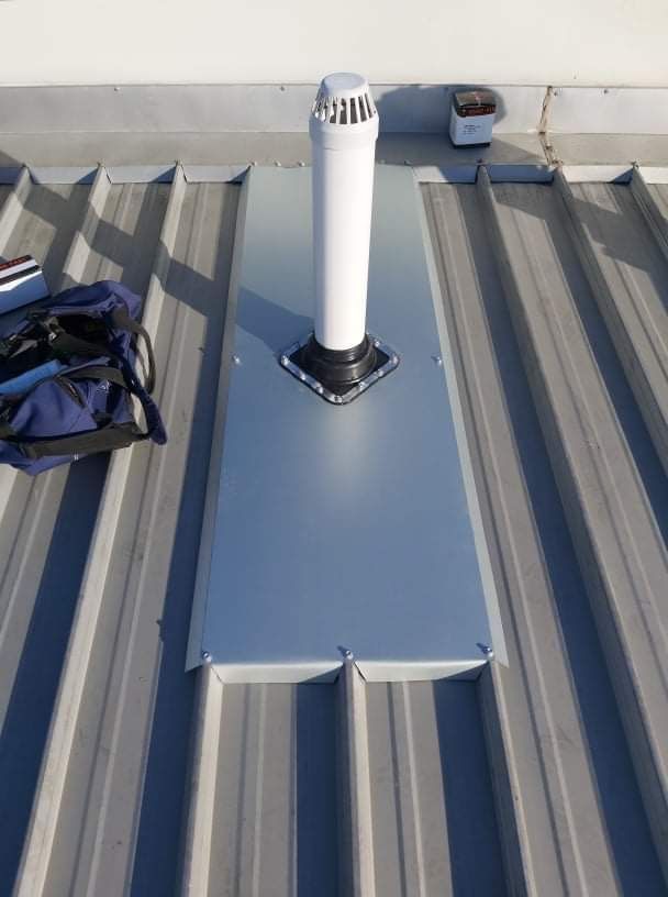 A white pipe is sitting on top of a metal roof — Kimick Roofing Solutions In Wyong, NSW