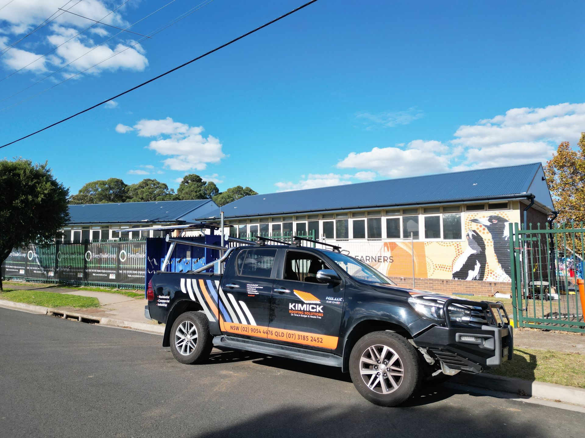 A black truck is parked on the side of the road in front of a building — Kimick Roofing Solutions In Wyong, NSW