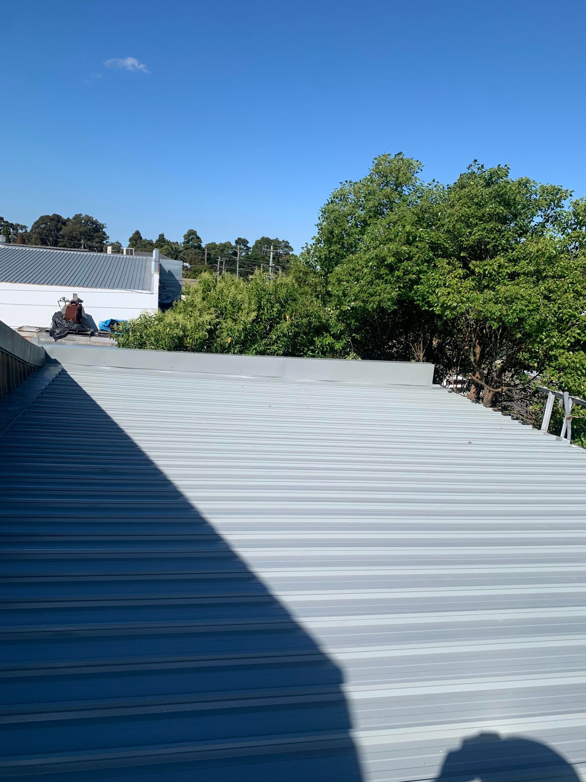 A roof with a blue sky and trees in the background — Kimick Roofing Solutions In Wyong, NSW