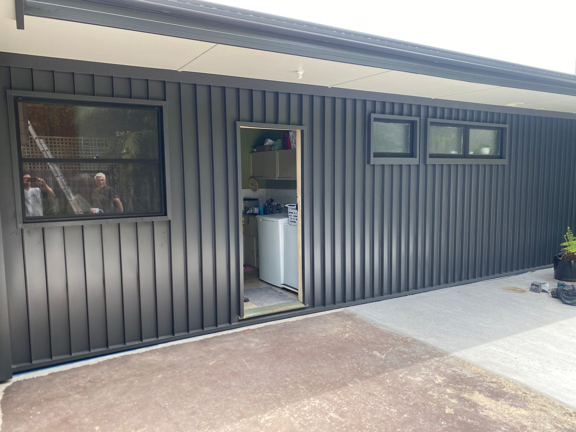 A black house with a washer and dryer in the backyard — Kimick Roofing Solutions In Wyong, NSW