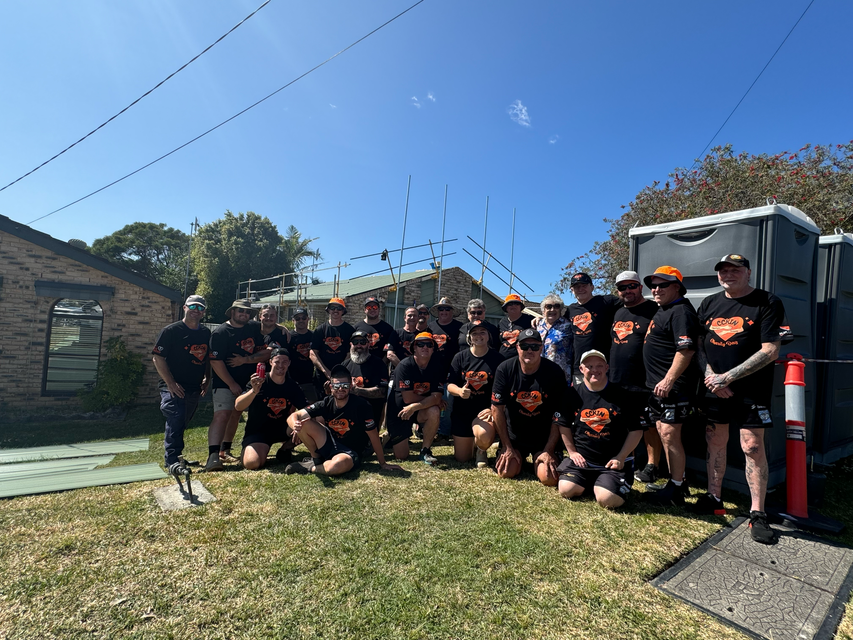 A group of people are posing for a picture in front of a house — Kimick Roofing Solutions In Wyong, NSW