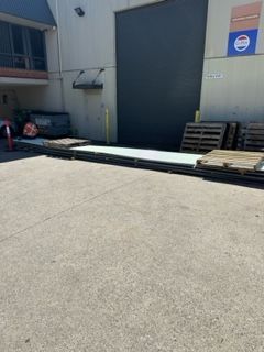 A lot of pallets are sitting on the ground in front of a building — Kimick Roofing Solutions In Wyong, NSW