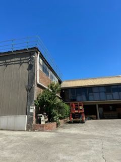 A large building with a red truck parked in front of it — Kimick Roofing Solutions In Wyong, NSW