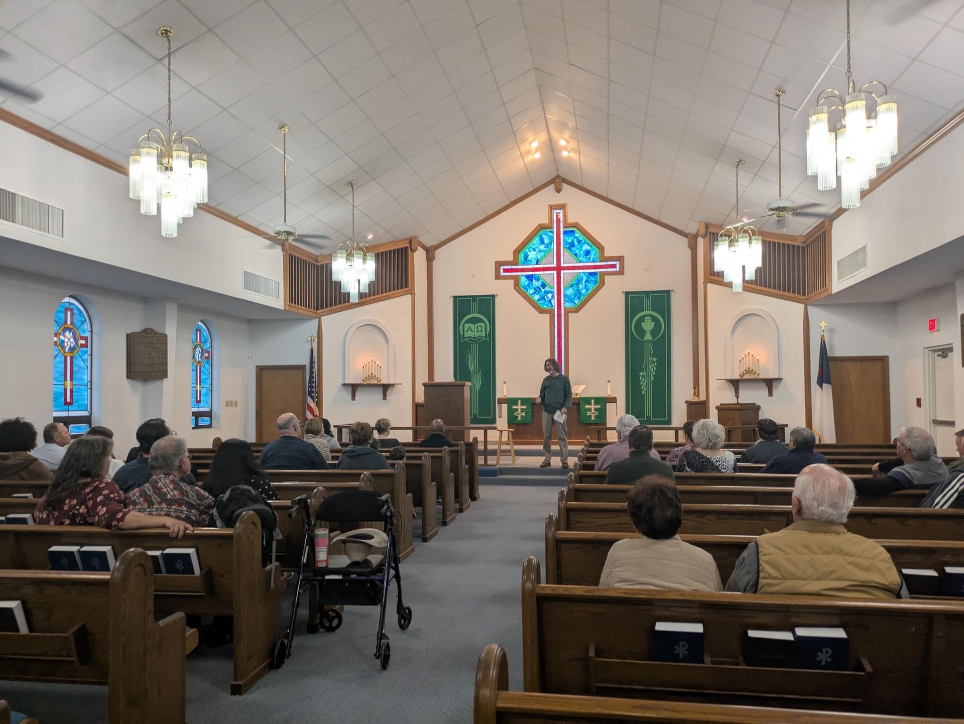 People gathered in a church during a service, listening to a speaker at the altar.