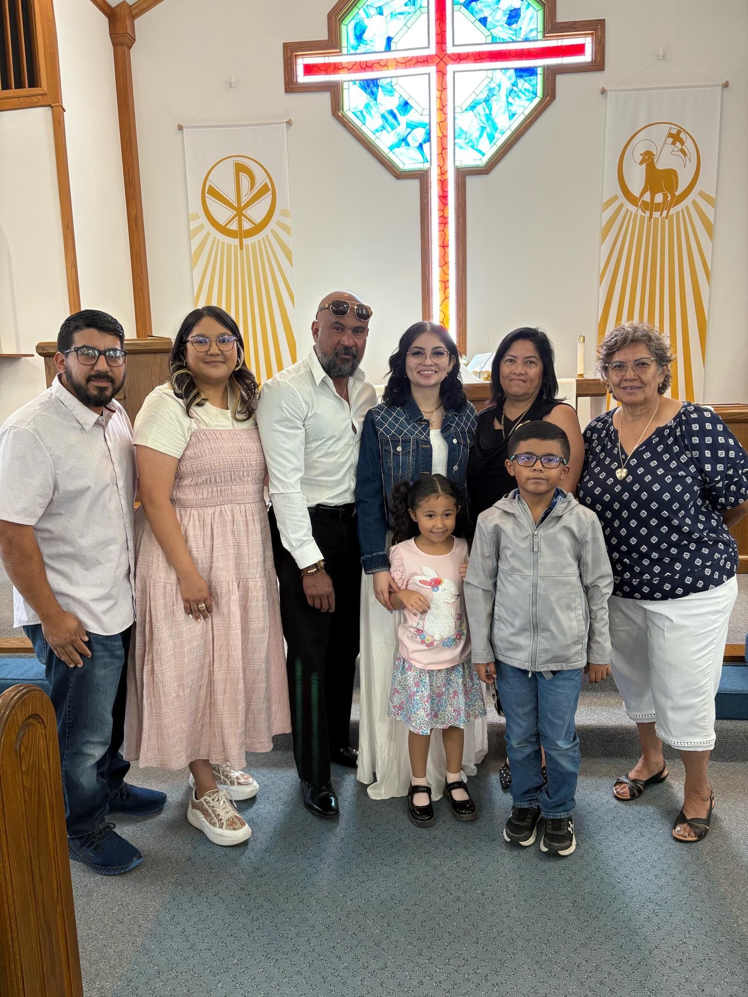 Group of people posing for a photo in a church, near a cross.
