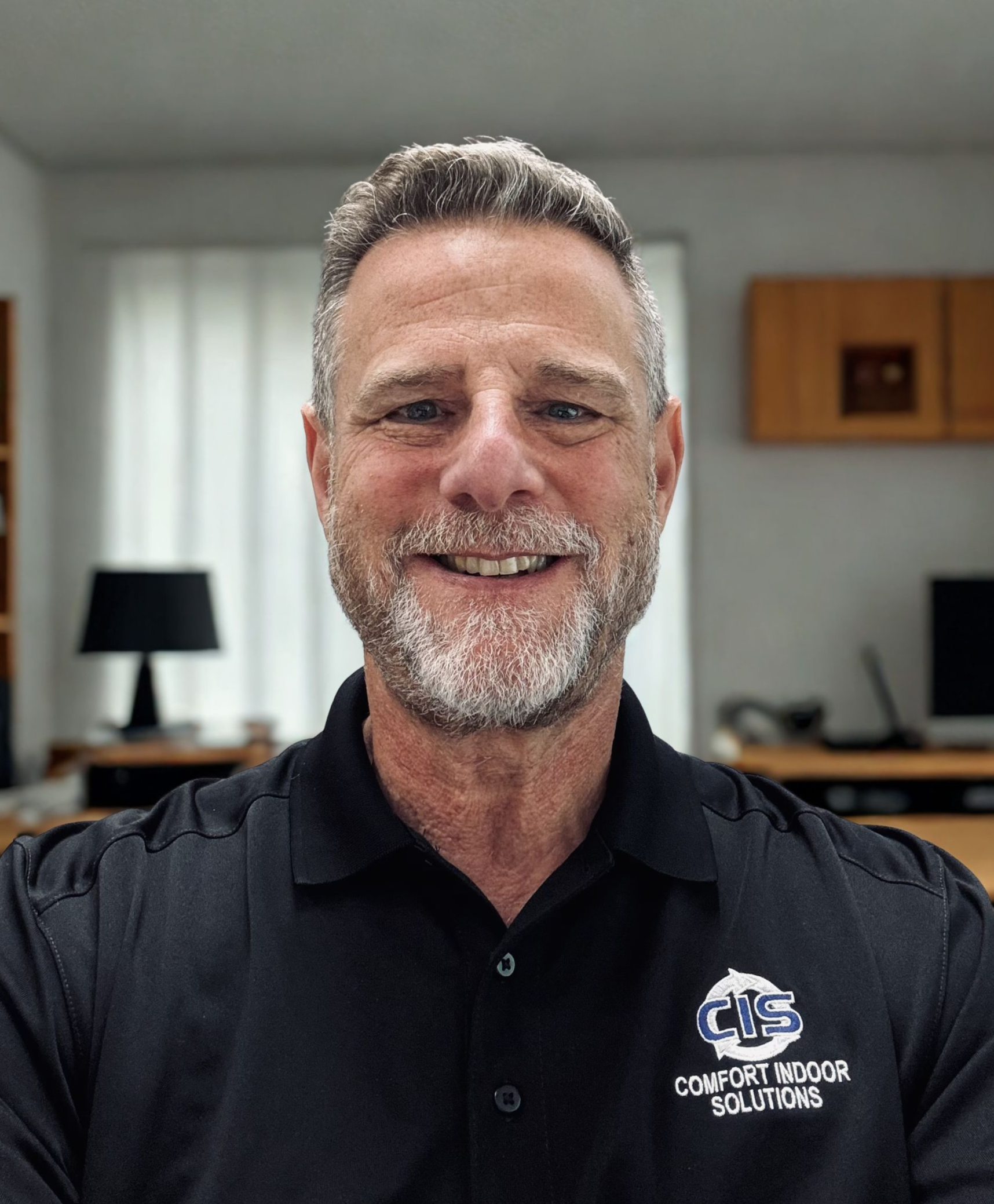 Smiling man in a dark polo shirt against a plain light background