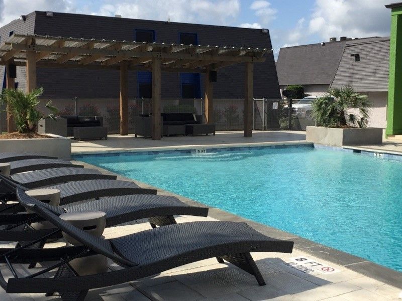 Backyard pool with lounge chairs and a covered patio under a sunny sky