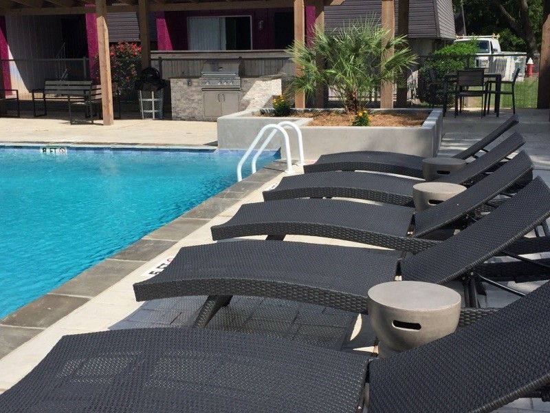 Poolside lounge chairs beside a turquoise swimming pool on a sunny patio