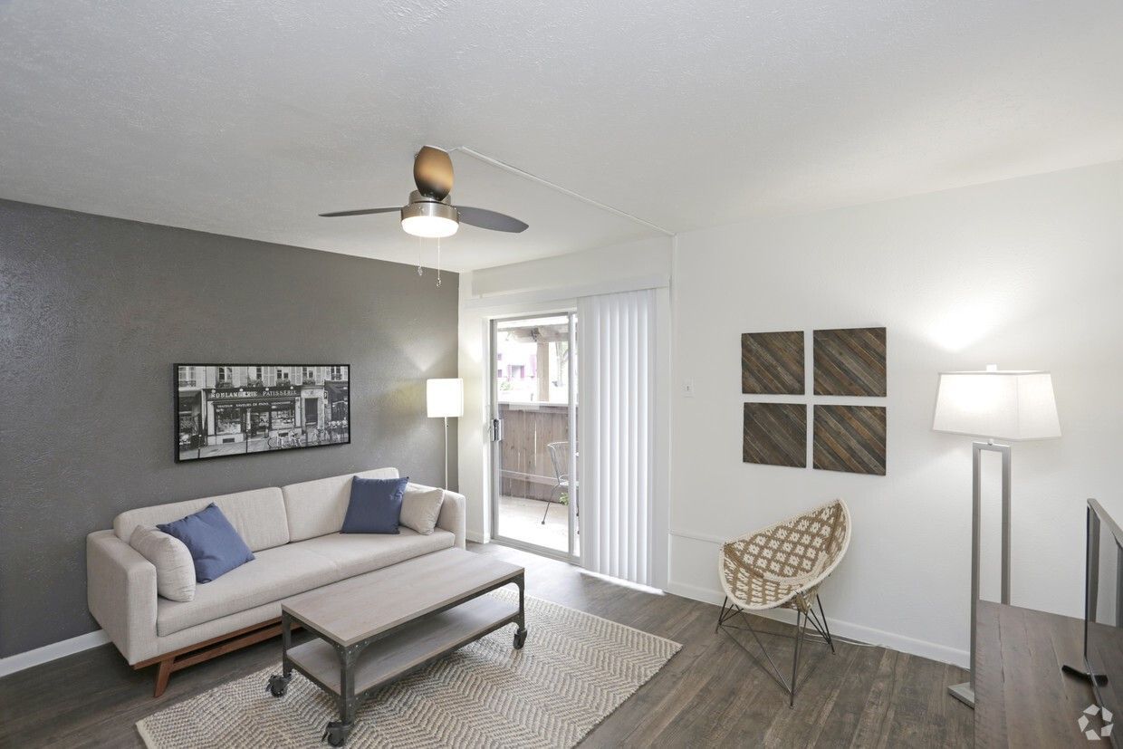 Bright living room with gray sofa, coffee table, floor lamp, wall art, and sliding glass door.