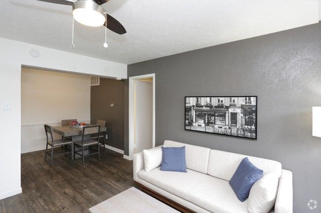 Bright living room with white sofa, blue pillows, dining area, and gray accent wall