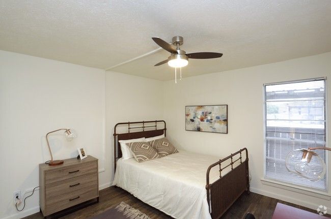 Small bedroom with metal bed, dresser, ceiling fan, and window with blinds
