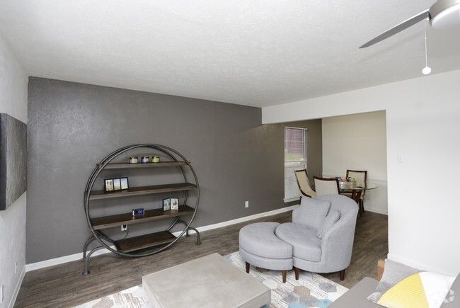 Gray living room with a circular bookshelf, light chaise lounge, and ceiling fan