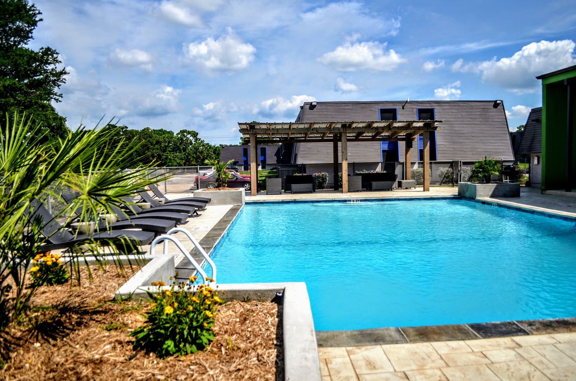 Outdoor swimming pool with blue water, lounge chairs, and a shaded cabana under a bright sky