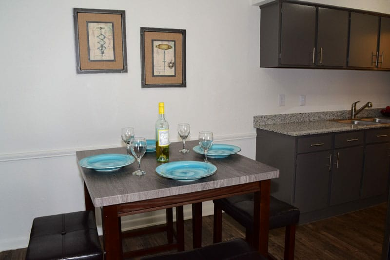 Small dining nook with a dark wood table set for four beside a kitchen counter.