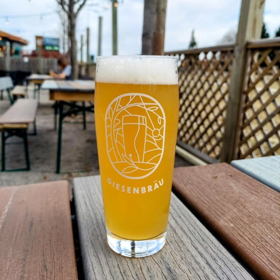 Tall glass of amber beer with foam on an outdoor café table, branded