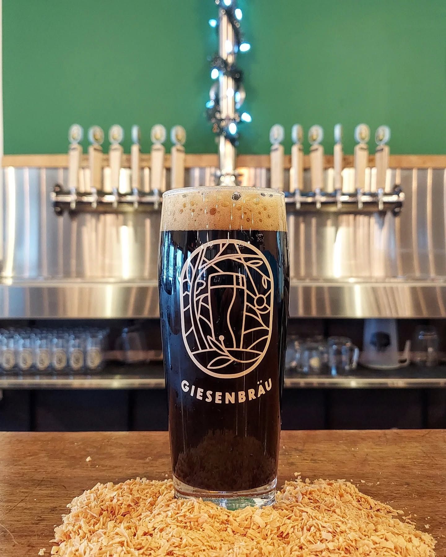 Tall glass of red beer with a foamy head on a wooden table in a bar