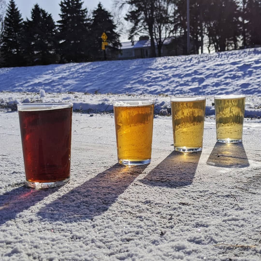 Pint of amber beer with foam on an outdoor patio in sunlight