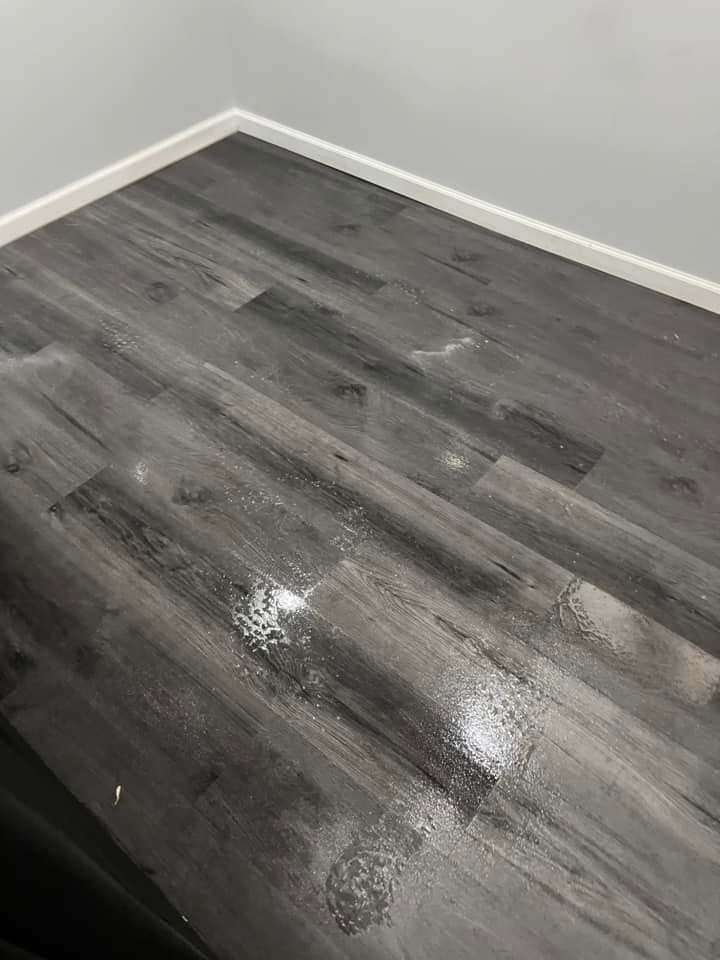 A room with a gray wooden floor and white walls.