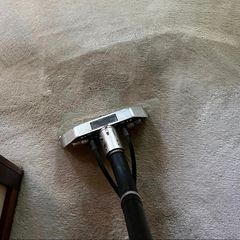 A vacuum cleaner is cleaning a carpet in a living room.