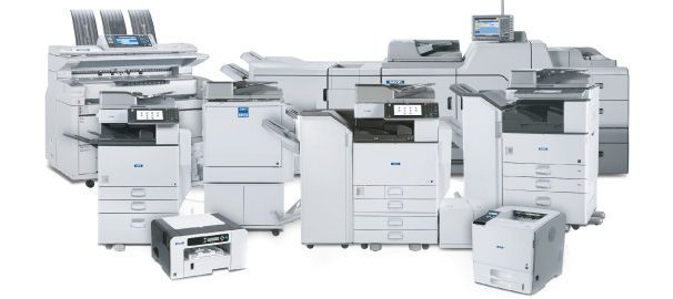 Several large white office printers and copiers arranged together on a white background
