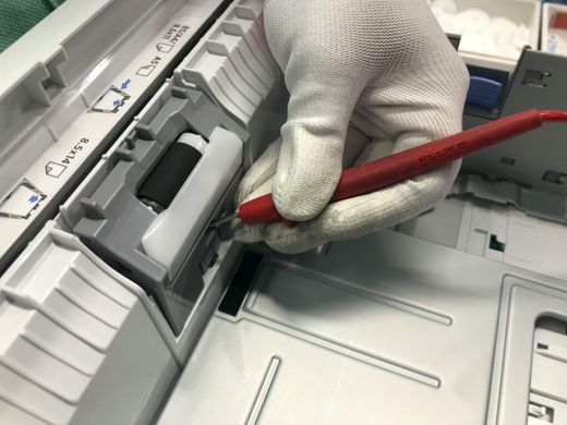 Gloved hand using a red pencil on a copier or printer control panel