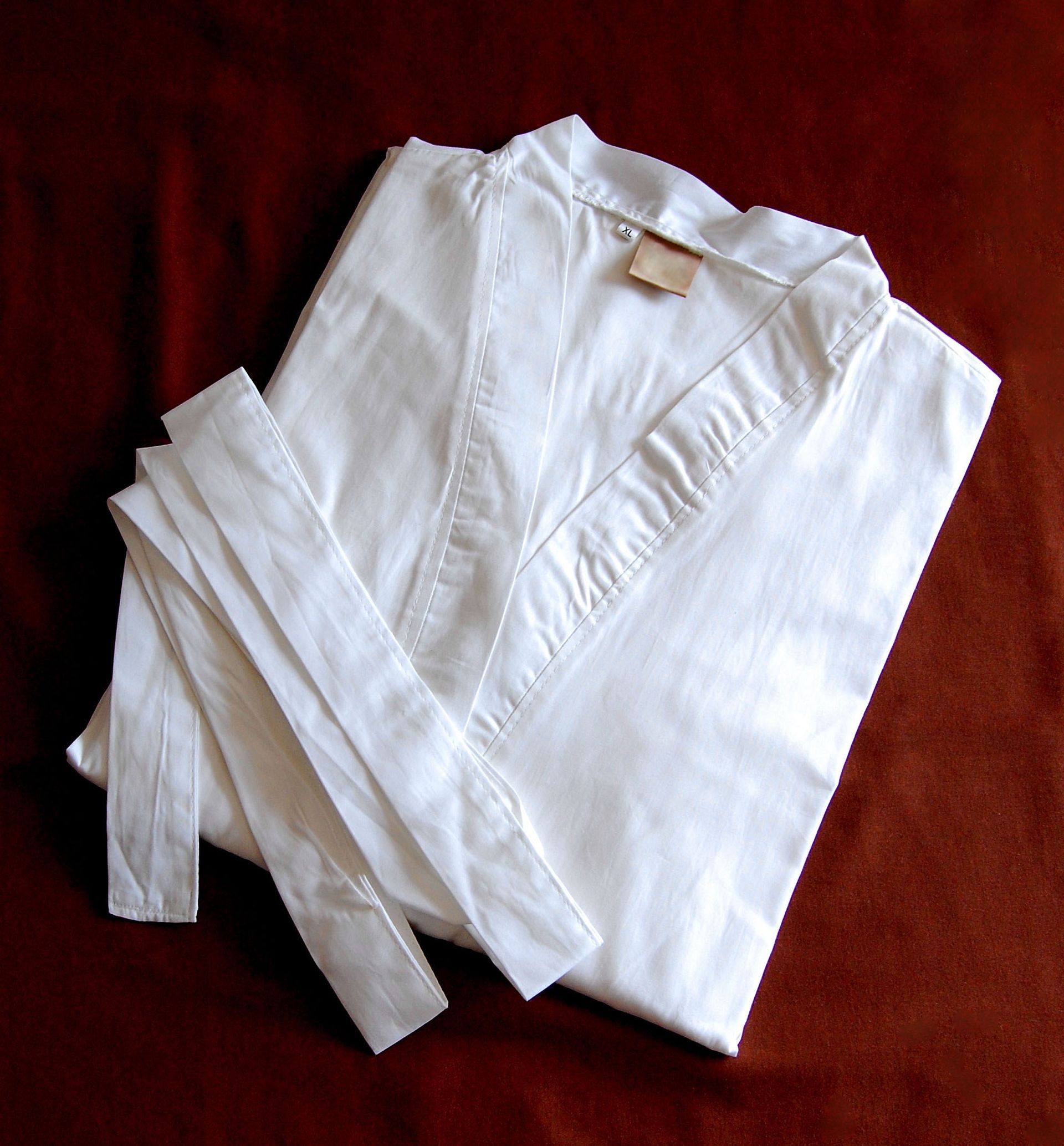 White folded robe with belt on a maroon background.