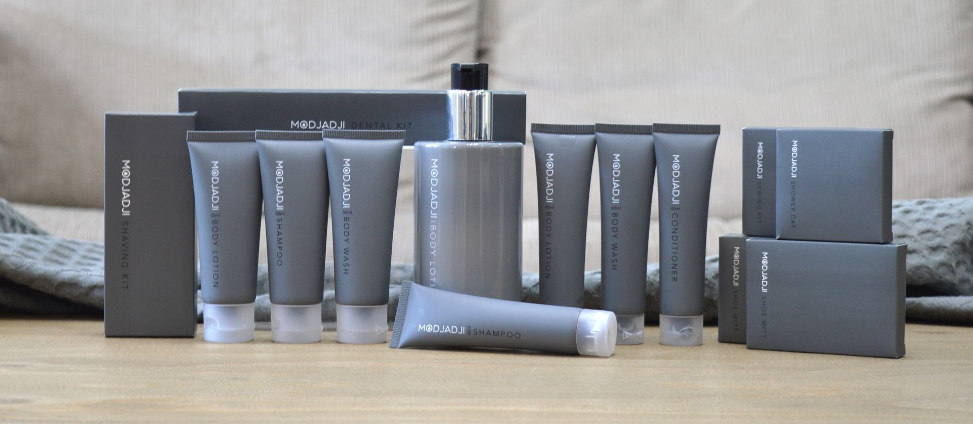 Collection of gray skincare products, including tubes, bottles, and boxes, arranged on a wooden surface.
