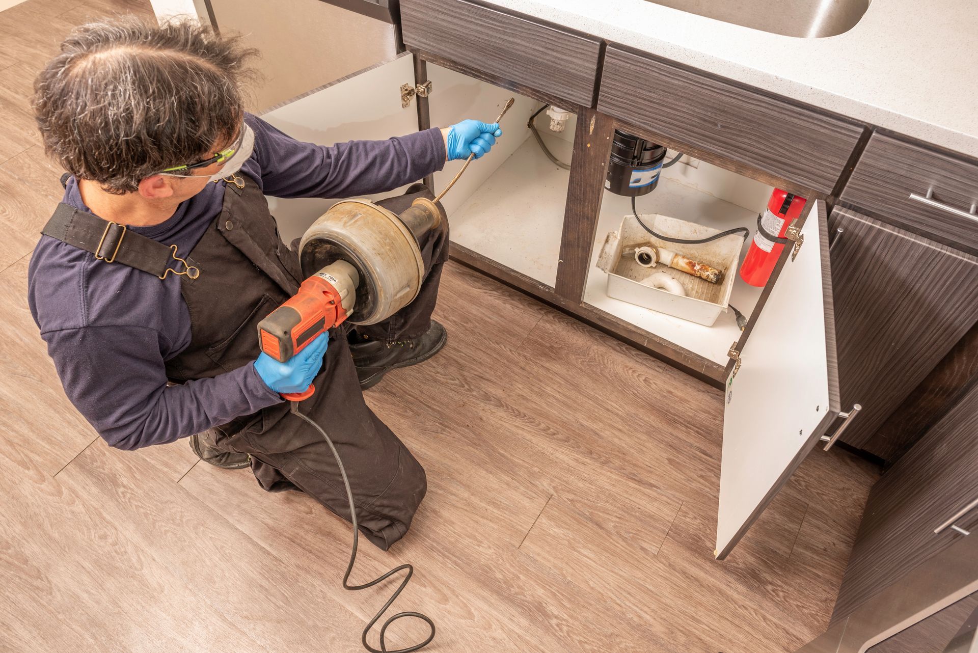 Plumber preparing to clear a clogged drain with a plumbing snake. Plumber preparing to clear a clogged drain with a plumbing snake.