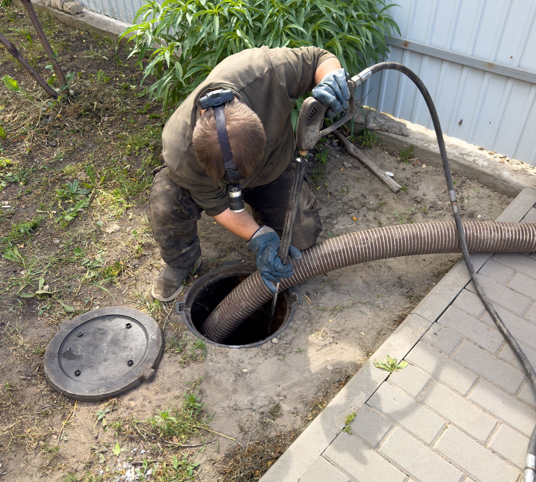 A sewer worker in gloves repairs an underground pipeline.
